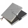 Toma fotográfica de libretas promocionales con tapa rígida en colores gris y negro, diseño de líneas geométricas abstractas, broche magnético y separador de listón para grabado empresarial.