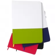 Toma fotográfica de libretas promocionales con cubierta flexible en color verde manzana y banda elástica de cierre, sobre una pila de cuadernos en colores variados para personalización empresarial.