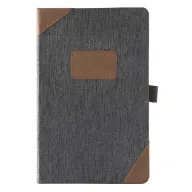 Toma visual de libretas promocionales ejecutivas en acabado textil gris con esquineros y placa central de curpiel café, además de sujetador elástico para bolígrafo ideal para grabado de marcas.